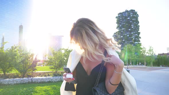 Attractive woman using smartphone and headset in park alt