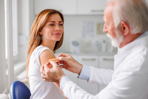 General practitioner applying medical patch to female patient after vaccination
