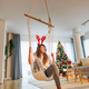 Woman sitting in hanging swing chair and relaxing at home on Christmas day - PhotoDune Item for Sale