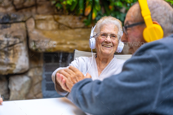 Happy elder people using headphones and smiling in a geriatric