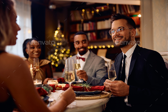 Happy man enjoying in conversation and dinner with his friends at dining table on New Year's eve.