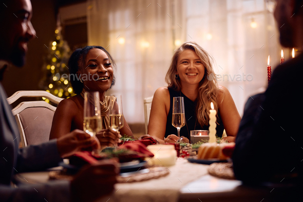 Happy women enjoying in conversation with friends during dinner party on New Year's Eve.