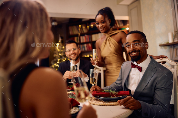 Happy black man talking to his friends during Christmas dinner party.