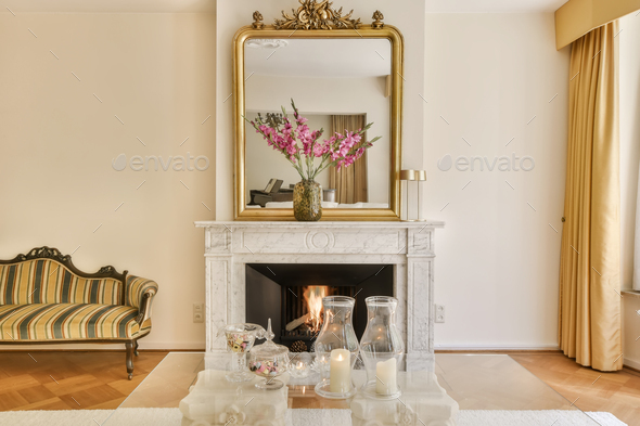 a living room with a fireplace and a gold mirror