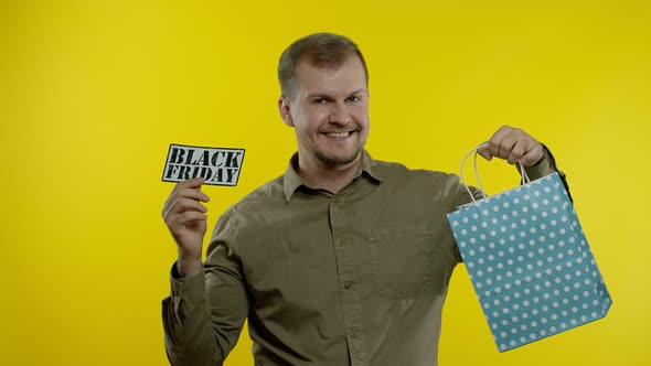 Man Showing Black Friday Inscription From Shopping Bag, Smiling, Rejoicing Discount, Low Prices alt