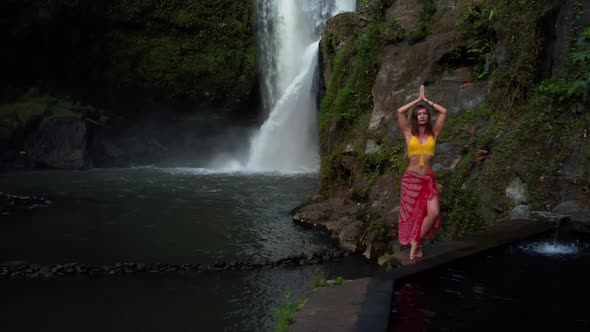 Asian Woman Statys in Front of Waterfall alt