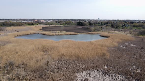 Panoramic view of open land with retention pond and dry grass in the midwest.