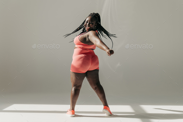 Full length of plus size woman exercising in gym stock photo
