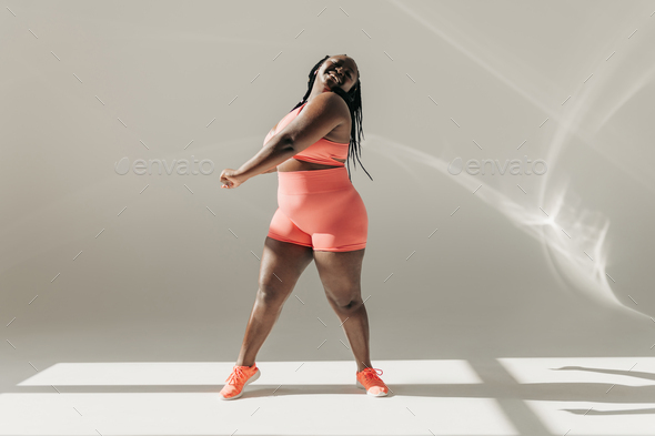 Full length of plus size woman exercising in gym stock photo