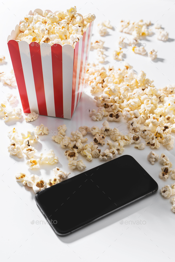 Classic popcorn bucket and smartphone with blank screen on white background