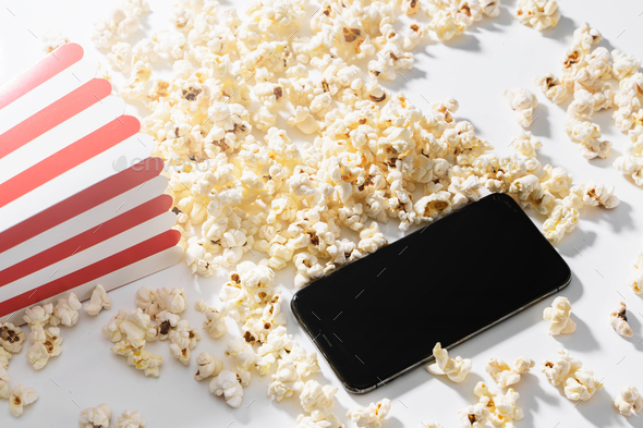 Classic popcorn bucket and smartphone with blank screen on white background
