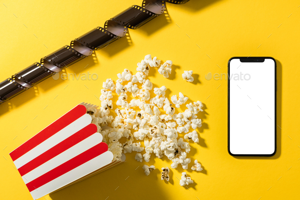 Classic popcorn bucket and smartphone with blank screen on yellow background
