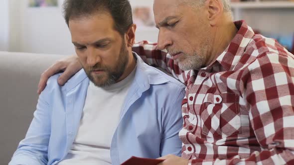 Father Telling Stories to His Son Watching Photos From Family Album, Memories alt