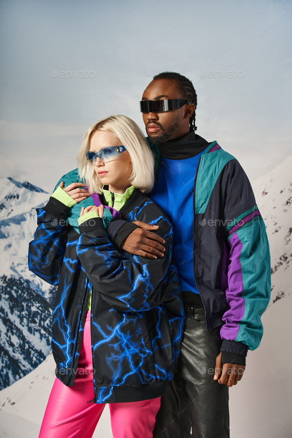 beautiful diverse couple in fashionable winter clothes hugging warmly and  looking at camera Stock Photo by LightFieldStudios