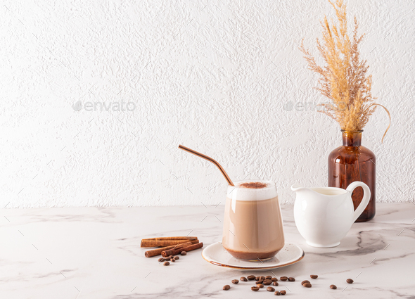 Beautiful stylish still life with a large glass of freshly brewed cappuccino coffee, a jug of milk