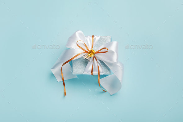 Gift boxes wrapped in blue and silver paper with white and gold ribbon bows.  Stock Photo by TaniaJoy