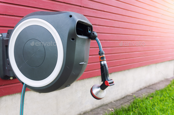 Wall Mounted Retractable Hose Reel. Modern garden lawn watering tip hose  with sprinkler hanged at Stock Photo by Gorlovkv