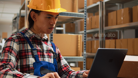 Asian guy organizing boxes with supplies on shelves Stock Photo by DC_Studio