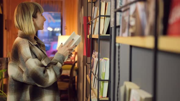 Portrait of Clever Student with Open Book Reading It in College Library alt