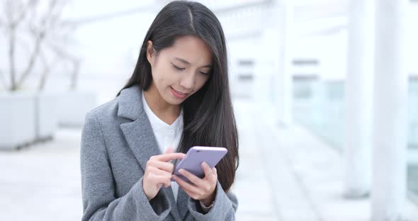 Businesswoman Sending SMS on Cellphone at Outdoor alt