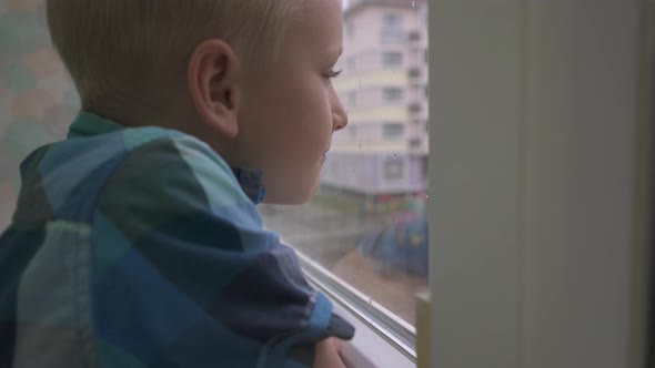 Boy Looking Out the Window Waiting for Parents at Home Alone