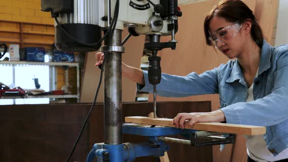 Asian carpenter female drill wood by drilling  machine in wood workshop factory