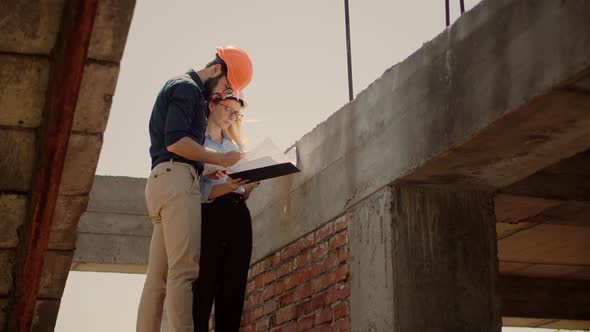 Two Architects Working On Building Model Blueprints. Engineers In Safety Helmet Construction House. alt