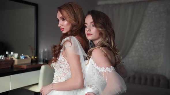 Two Young Models Posing in Front of the Photographer in a Wedding Dress. alt
