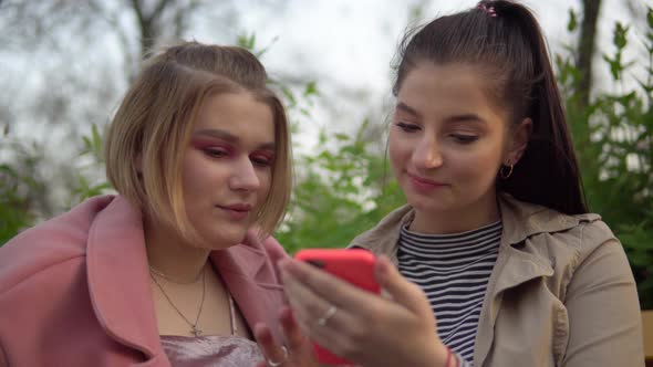 Two Attractive Happy Girls Looking at Phone Screen Laughing Friendship Concept