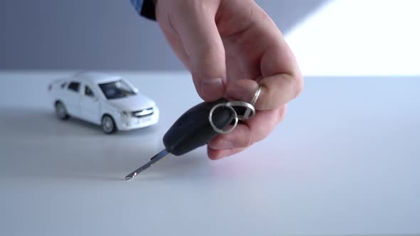 A Man's Hand Putting Some Car Keys with Remote Control on the Table alt