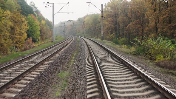 Drone flying along the railroad tracks in autumn forest.