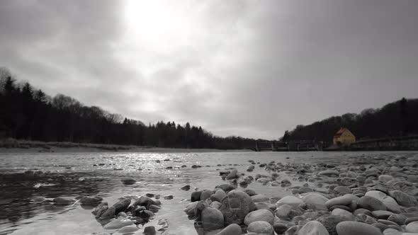 Black and white flowing river in front of a weir from lower, stony perspective with a colorkeyed yel alt