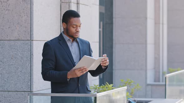 Serious Confident Black Man Wearing Suit Holding Day Planner Reading Paper Book or Business Notebook alt