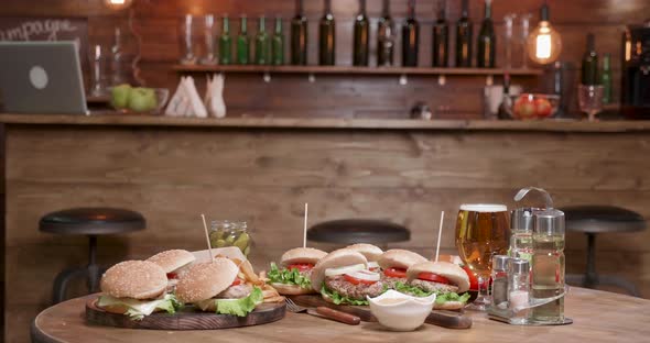 Very Big Selection of Burgers on Wooden Table in Front of a Bar alt