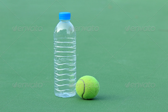 Tennis ball on tennis court with bottled drinking water