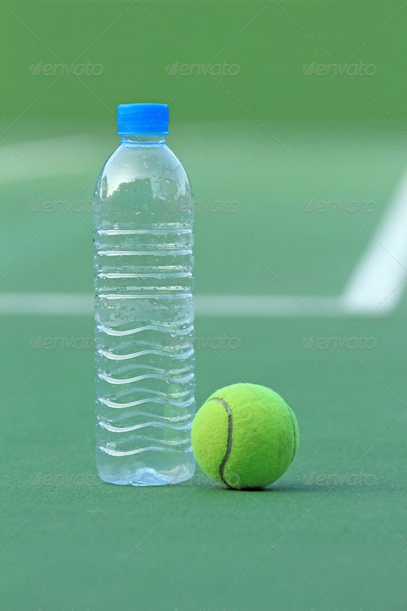 Tennis ball on tennis court with bottled drinking water