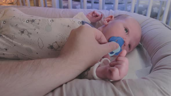 A newborn baby, one month old, cries in bed without a pacifier