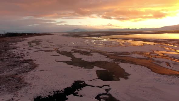 Aerial view of frozen landscape covered in snow during colorful sunset alt