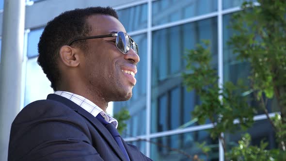 Young Black American Businessman Smiling: Corporate Buildings in Background      alt