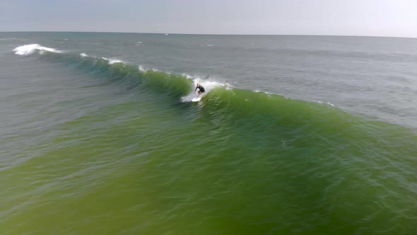 Epic drone tracking shot of surfer riding a wave. alt