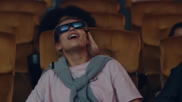 young caucasian couple laughing while watching 3D movie in movie theater.