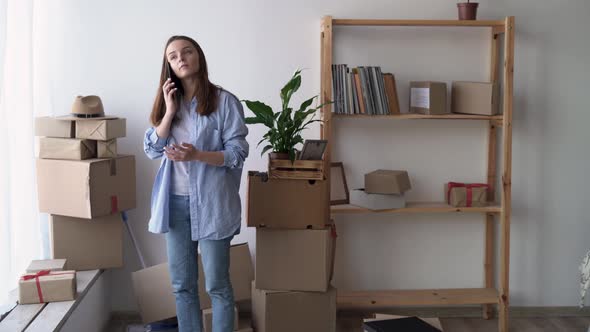 Woman Moving to a New House Talking on the Phone with a Carrier Delivering Things Home Settling in alt