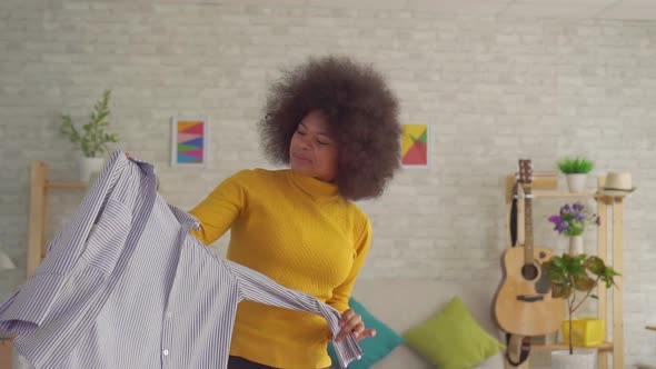 African Woman with an Afro Hairstyle Trying on Clothes in Front of a Mirror in His Modern Apartment alt