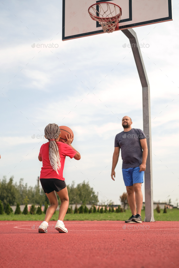 Kid takes aim to throw a ball into a basketball basket while playing