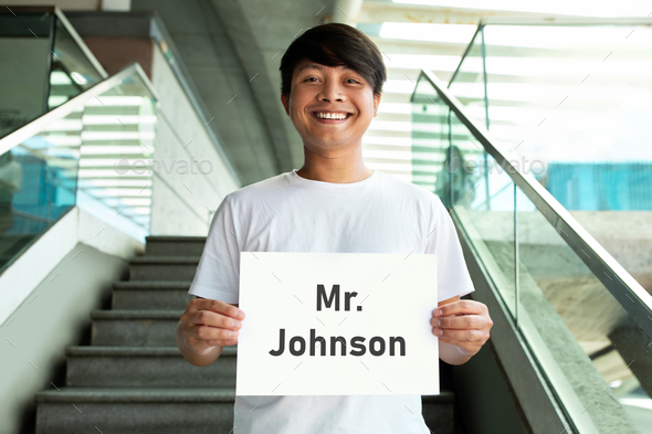 Cheerful millennial asian guy holding placard with name