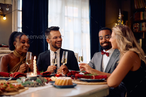 Multiracial group of friends talking while having dinner at dining table at Christmas.