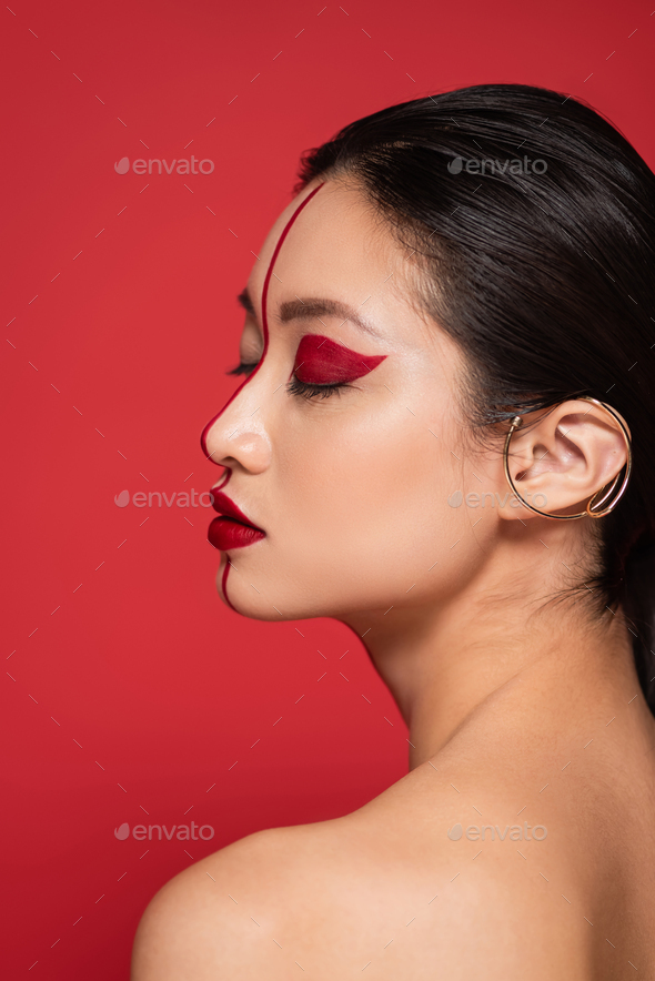 profile of asian woman with closed eyes and artistic makeup on perfect face isolated on red