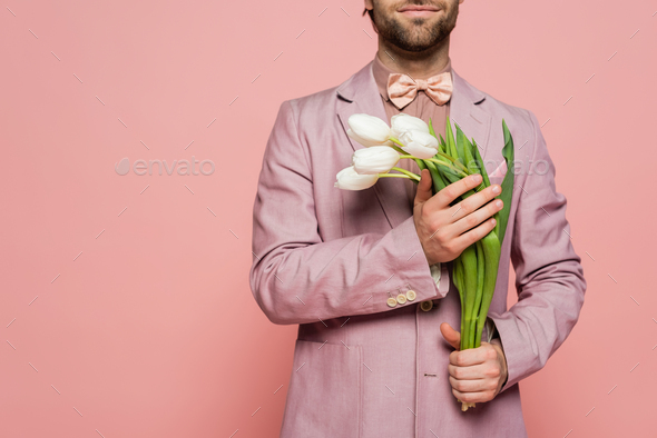 Cropped view of bearded host of event holding tulips isolated on pink
