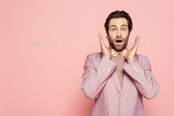 Shocked host of event looking at camera on pink background