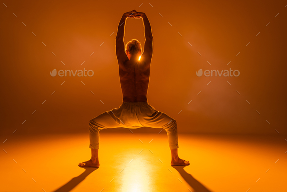Calm female child sitting on mat in yoga pose with raised arms. Little girl  closed eyes and training Stock Photo by jeannierv
